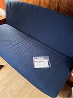 Front view of navy IKEA Beddinge futon sofa bed with upholstered cover