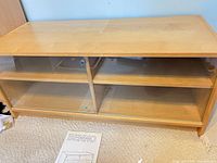 Front view of IKEA BENNO TV stand showing sliding glass doors and interior shelf