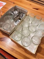 Two trays holding clear glass canning jars and stacked metal lids