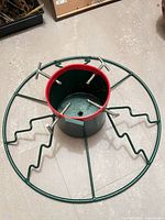 Top view of metal Christmas tree stand showing circular frame, central cylinder, and six bolt clamps