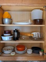 Full cabinet view showing mixed kitchenware items on three shelves