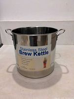 Front view of stainless steel brew kettle showing label and handles