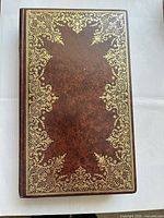 Closed leather-bound volume showing brown cover with ornate gilt border