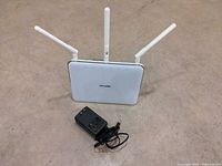 Front angled view of router with three antennas and power adapter placed nearby