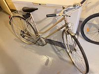 Full left-side view of bicycle showing frame style, rack, fenders, light, bell, tool kit