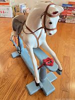 Full view of white wooden rocking horse on blue base