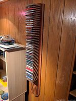 Full view of tall wall-mounted wooden CD rack filled with CDs