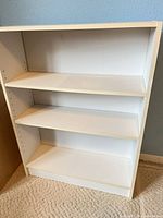 Front view of white laminate bookcase with three shelves