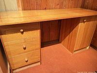 Front view of desk showing three drawers on left pedestal and cabinet door on right pedestal