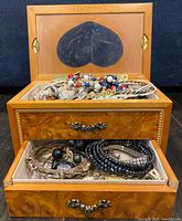 overall view of open jewelry box with top and drawers showing mixed jewelry