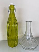 Green ribbed glass bottle and clear ribbed decanter side by side