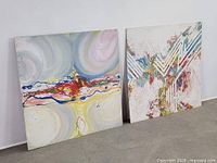 Both paintings leaning against wall, full view