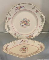 Top-down view of both porcelain pieces showing overall shape, floral pattern, pink band and gilt rims