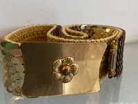 Full view of belt coiled showing buckle and fish-scale discs