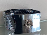 Belt coiled showing reflective fish-scale links and floral buckle front