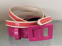 Coiled pink patent belt highlighting buckle detail