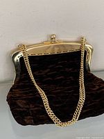Front view of brown velvet quilted purse with gold-tone frame and chain