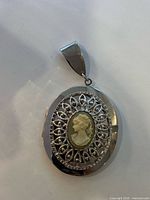 Front view of oval cameo locket showing filigree and cameo details