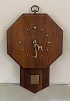 Front view of walnut octagon wall clock with brass markers and hands