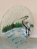 Full view of round glass plate showing heron illustration and textured surface