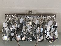 Front view of silver sequin clutch showing layered discs and kiss-lock clasp