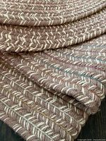 Folded view of oval braided rug showing edge detail and color pattern