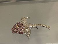 Full view of brooch showing pink rhinestone bloom, clear rhinestone leaves and stem