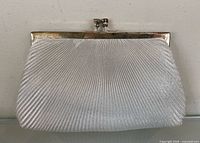 Front view of silver-tone pleated clutch showing fabric texture and metal frame