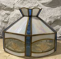 Overall view of hexagonal stained glass pendant light showing iridescent panels, blue accents and pressed flower lower panels