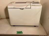 Front view of bread maker, closed lid, power cord visible