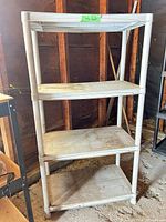 Full front view of the gray plastic shelving unit showing four shelves