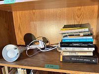 Stack of paperback natural history books and clip-on lamp on shelf