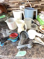 Full lot on countertop showing pitchers, measuring jugs, multiple sets of measuring cups and spoons, and glass creamer