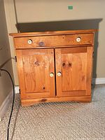Front view of wood cabinet showing drawer, doors, ceramic knobs