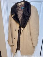 Front view of camel overcoat on hanger showing button front and faux-fur collar