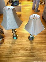 Both brass table lamps with shades shown on floor