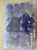 Clear box containing assorted sizes of black matte and glitter ornaments with hanging cords