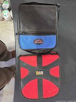 Black/blue and red/black zippered CD/DVD storage wallets on tabletop