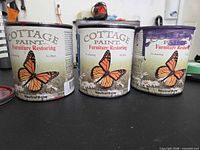 Three Cottage Paint cans front labels visible