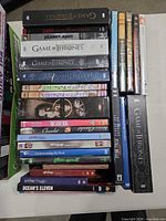 Stack of DVD and box sets including Game of Thrones, Planet of the Apes, Scarface and others on tabletop