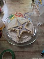Top view of glass bowl containing sand and starfish