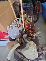 Lot overview showing bag of ornaments with lights, metal sleigh, plush moose figure, tabletop tree, tin candle holder