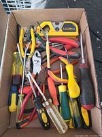 Box of assorted hand tools including screwdrivers, pliers, cutters, level, bit set