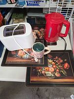 Lot overview showing kettle, toaster, mug and four placemats