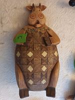 Front view of carved wooden cow showing quilt pattern and facial details