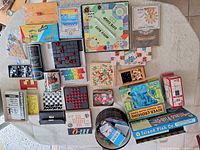 Top-down view of entire lot: boxed games, travel sets, puzzle can, poker chips, dice and loose game pieces