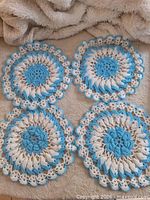 Four blue and white round crocheted doilies displayed on fabric background