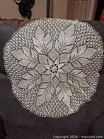 Large round ivory crochet doily draped over sofa