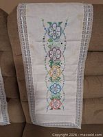 Full view of a runner showing embroidery pattern and lace edge