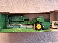 Side view of boxed John Deere 348 square baler model showing wheels, hitch, bale accessories